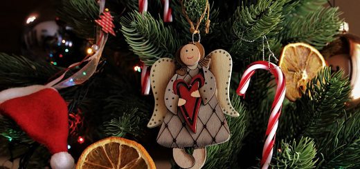 Weihnachtsengel aus Holz mit Herz in der Hand an geschmücktem Weihnachtsbaum